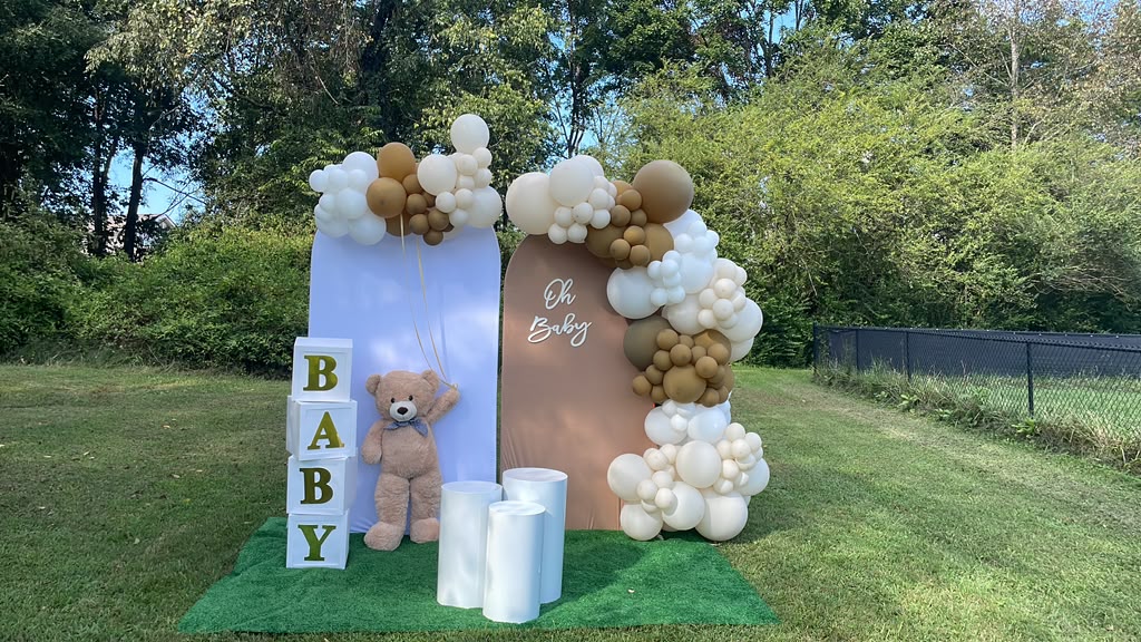 Neutral ivory and gold outdoor baby shower balloon installation with teddy bear
